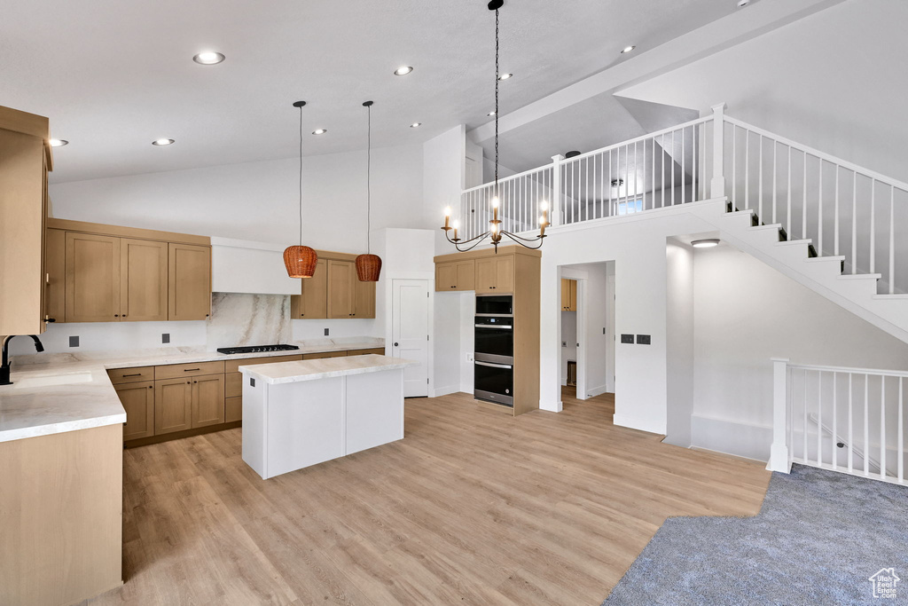 Kitchen with a sink, double oven, black gas cooktop, high vaulted ceiling, and light wood finished floors