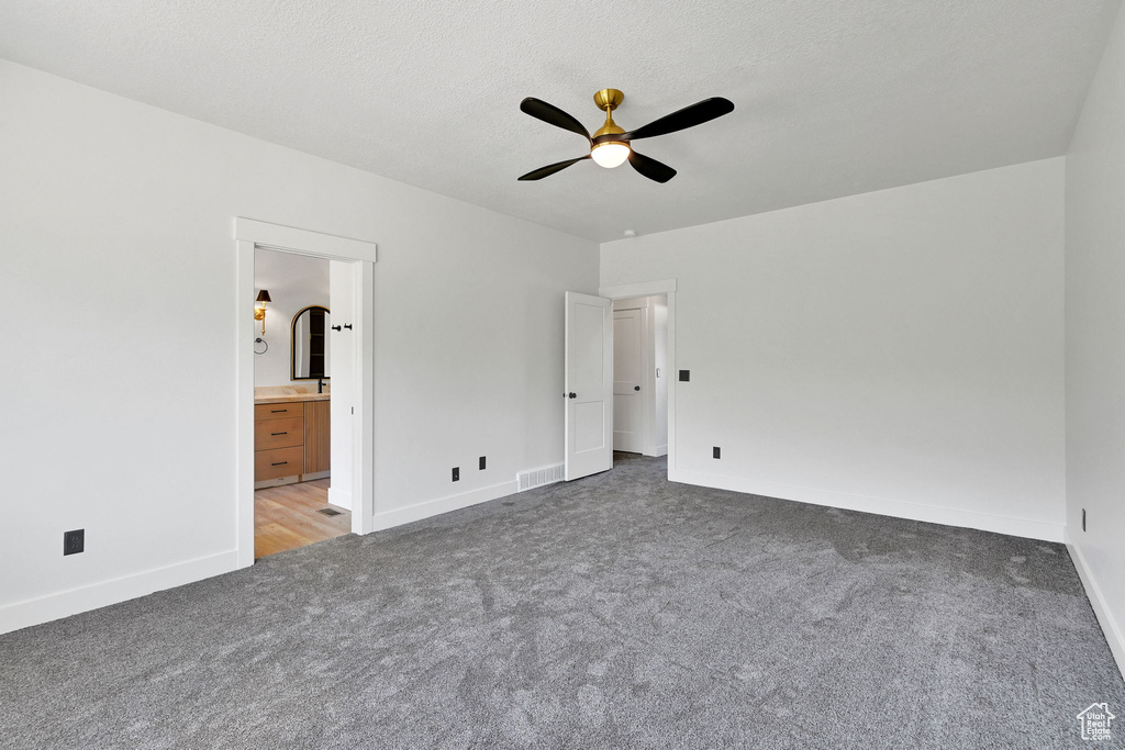 Unfurnished bedroom with carpet, baseboards, ensuite bathroom, and a ceiling fan