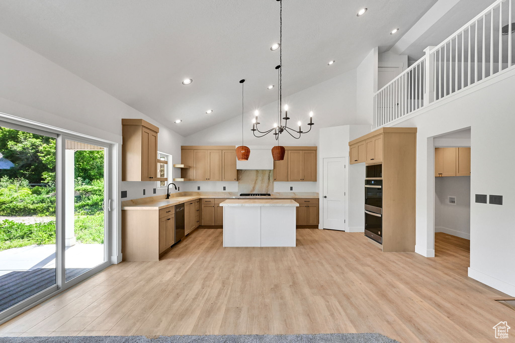 Kitchen featuring dishwasher, light countertops, a center island, light wood finished floors, and high vaulted ceiling
