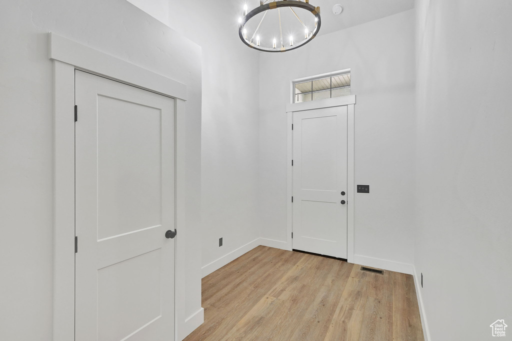 Entrance foyer with light wood-style flooring, a chandelier, and baseboards