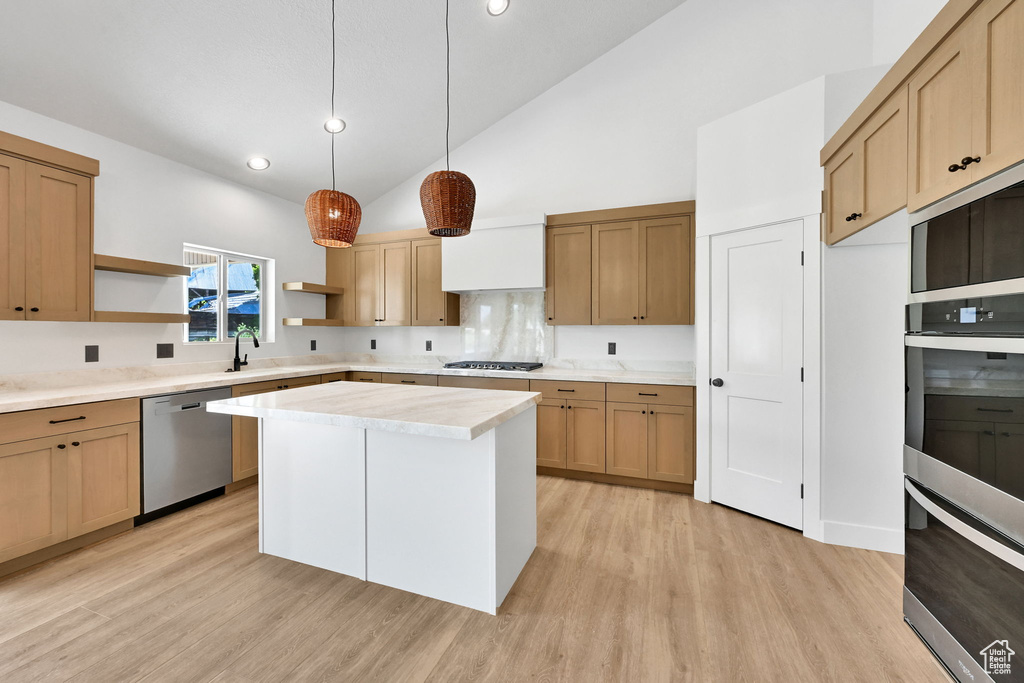Kitchen with appliances with stainless steel finishes, open shelves, light countertops, high vaulted ceiling, and a sink