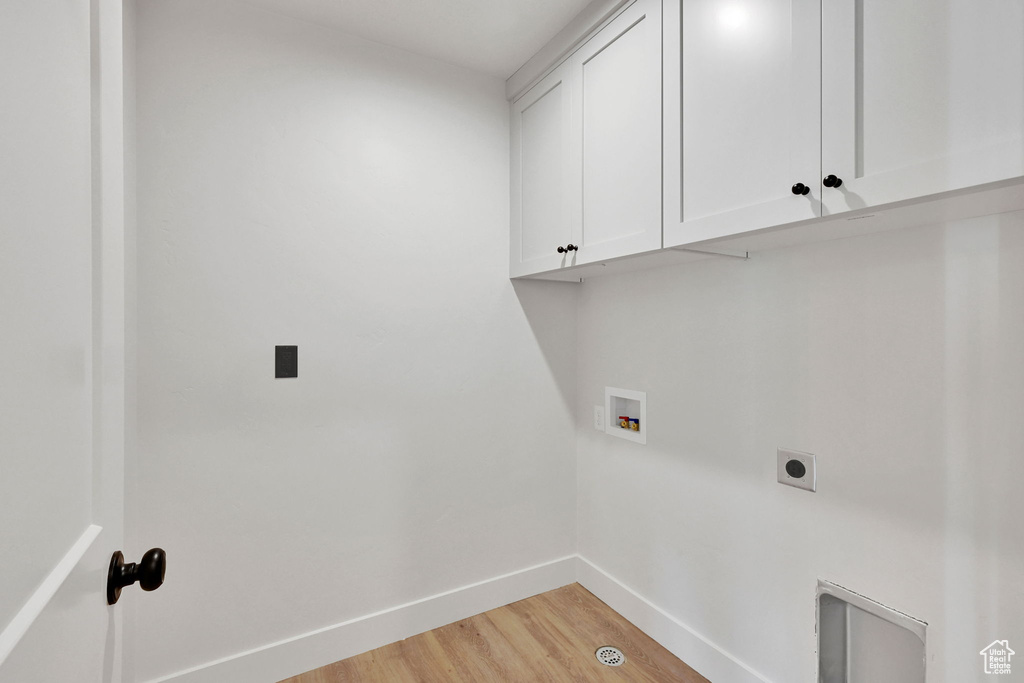 Laundry room featuring electric dryer hookup, baseboards, cabinet space, light wood-style flooring, and hookup for a washing machine