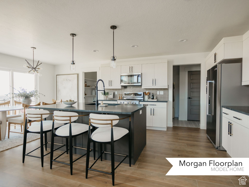 Kitchen featuring stainless steel appliances, dark countertops, a breakfast bar area, a sink, and recessed lighting