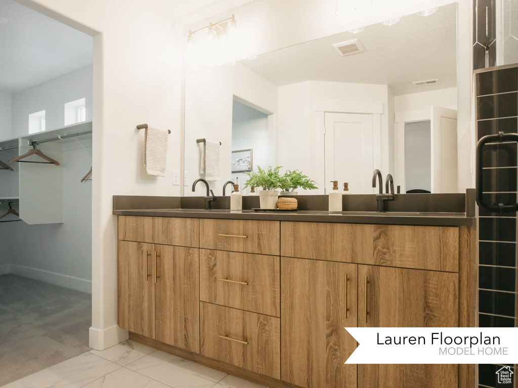 Bathroom featuring double vanity, marble finish floors, and baseboards