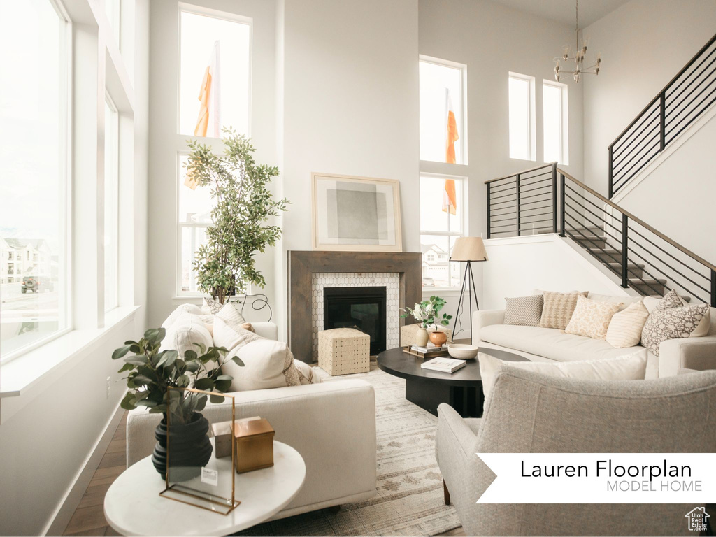 Living area featuring a high ceiling, plenty of natural light, a chandelier, and stairs