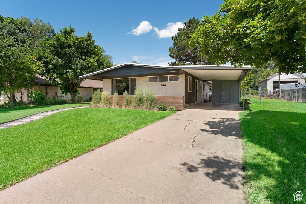 View of front of home featuring concrete driveway, brick siding, and a carport