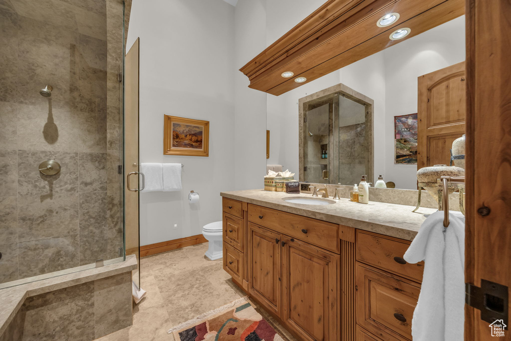 Full bath featuring a stall shower, toilet, vanity, and baseboards