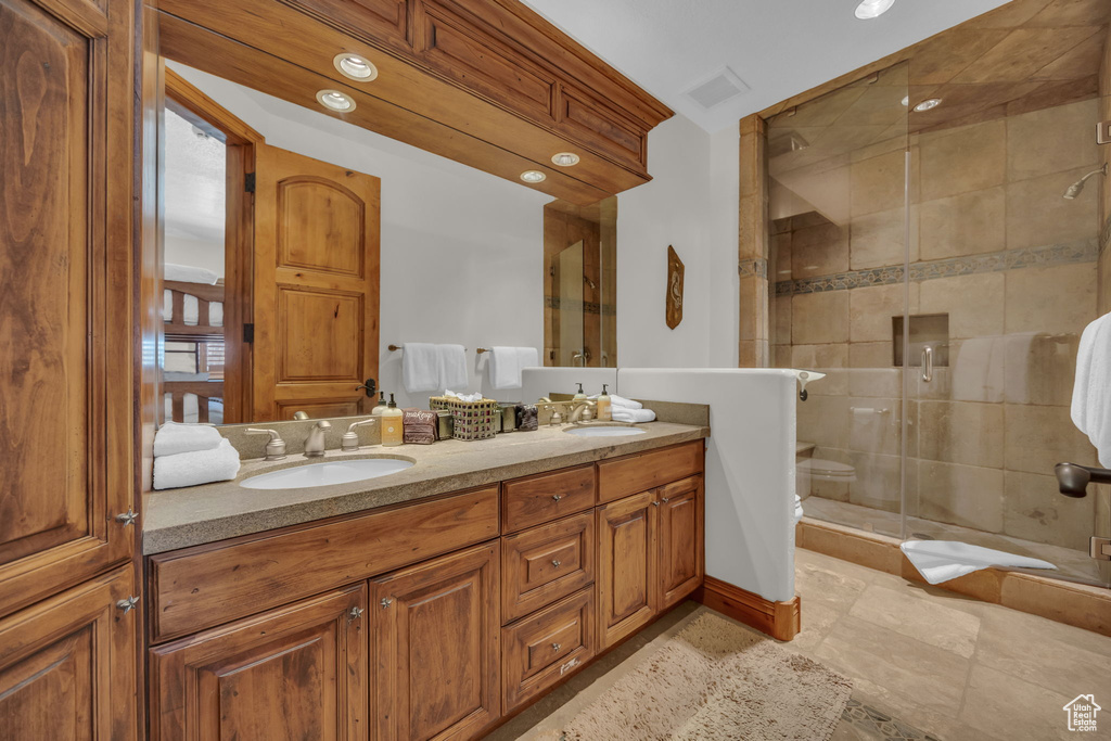 Full bathroom with double vanity, a shower stall, and recessed lighting