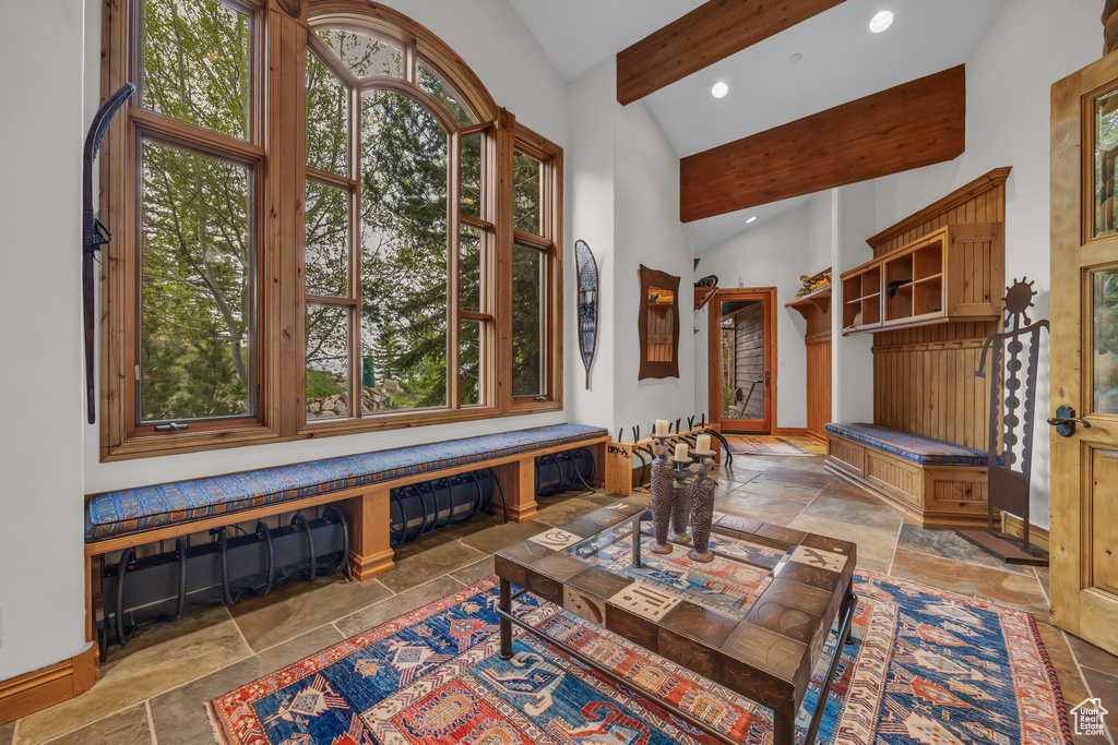 Living area with stone tile flooring, beamed ceiling, recessed lighting, high vaulted ceiling, and baseboards