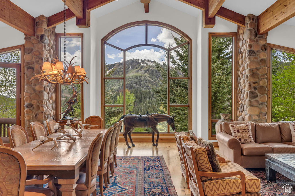 Sunroom featuring a chandelier, beamed ceiling, and a mountain view