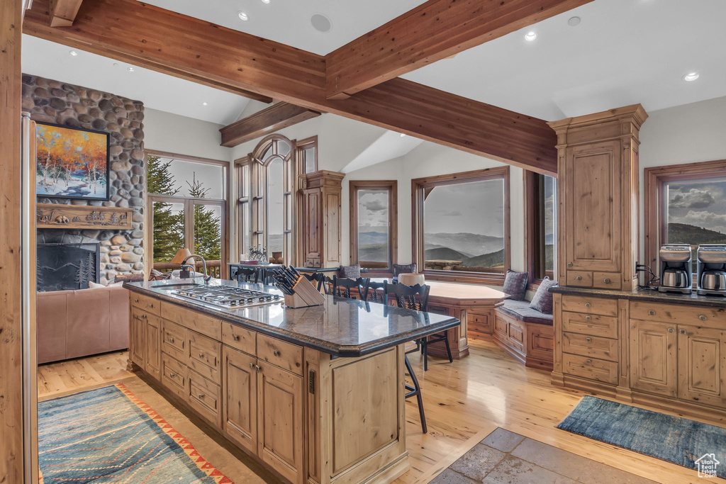 Kitchen featuring light wood finished floors, a kitchen bar, stainless steel gas stovetop, a fireplace, and recessed lighting