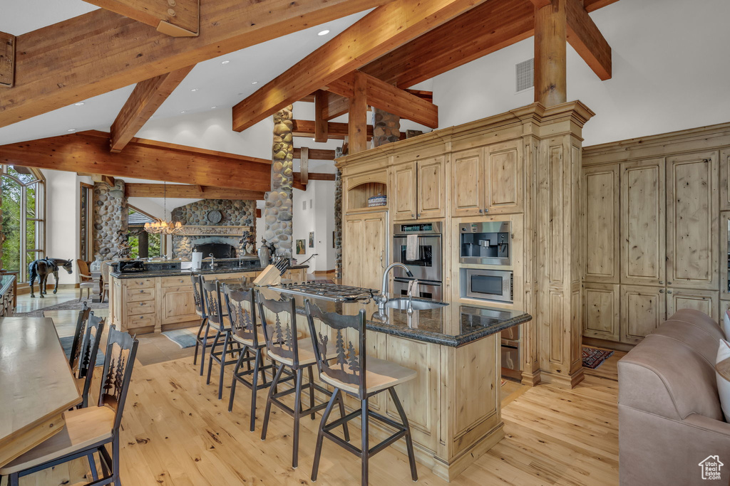 Kitchen with open floor plan, a sink, beam ceiling, light wood finished floors, and light brown cabinetry