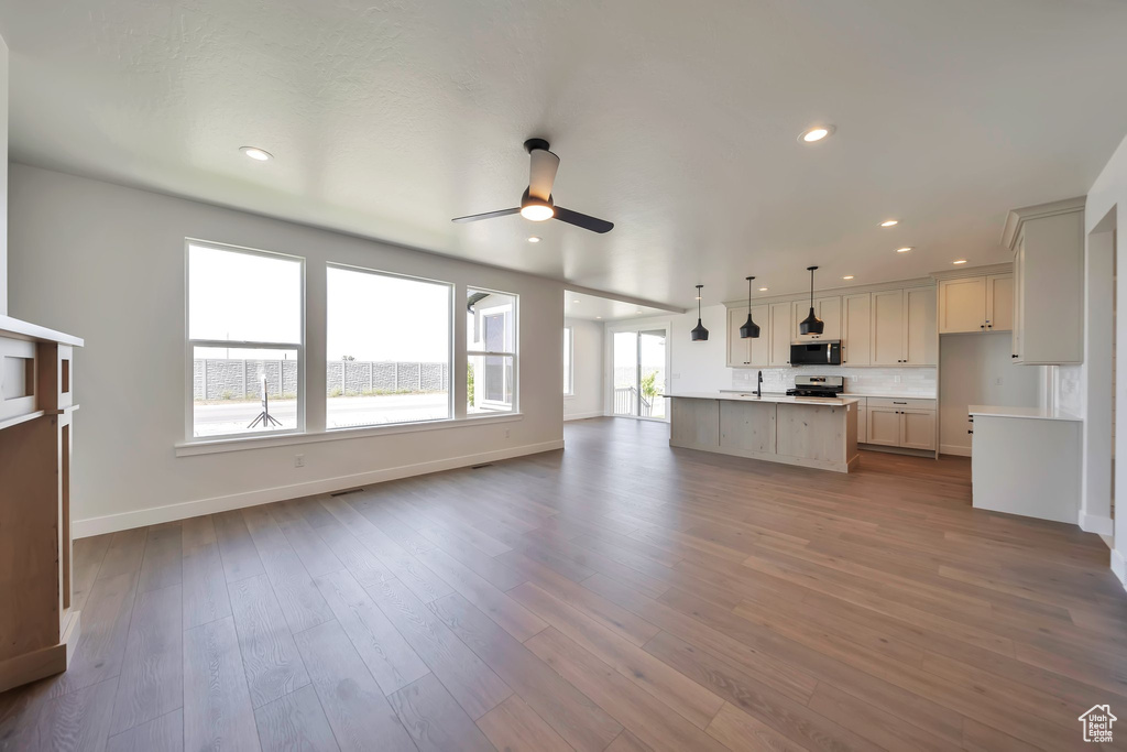 Unfurnished living room with a ceiling fan, baseboards, dark wood finished floors, a sink, and recessed lighting