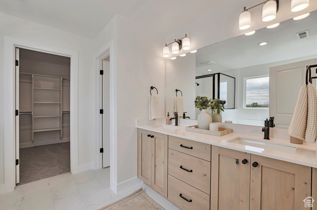 Bathroom with a walk in closet, double vanity, marble look tile flooring, a stall shower, and recessed lighting