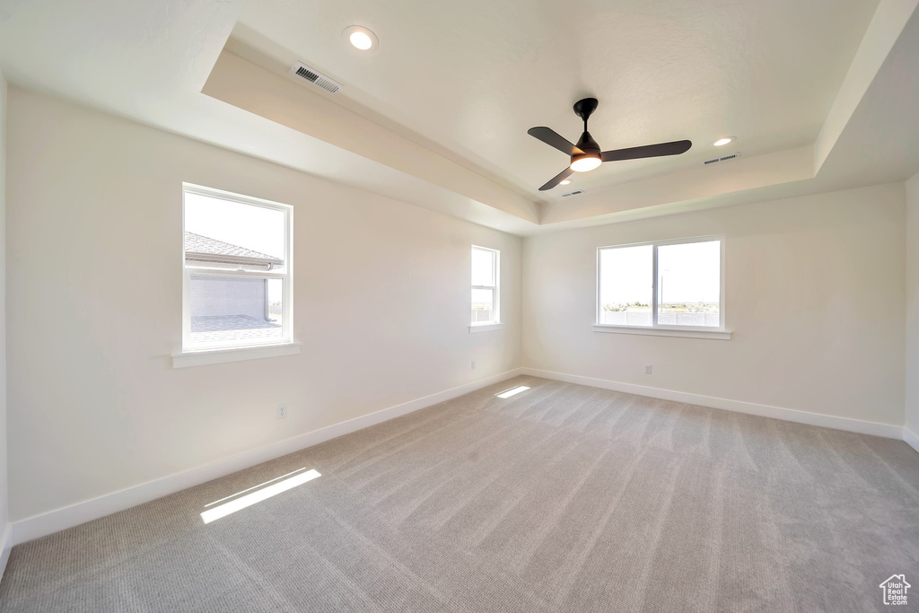 Unfurnished room with a tray ceiling, baseboards, light colored carpet, a ceiling fan, and recessed lighting