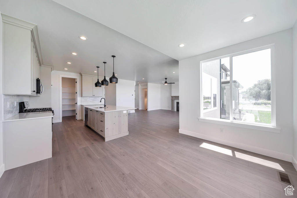 Kitchen with a sink, open floor plan, light countertops, wood finished floors, and decorative backsplash
