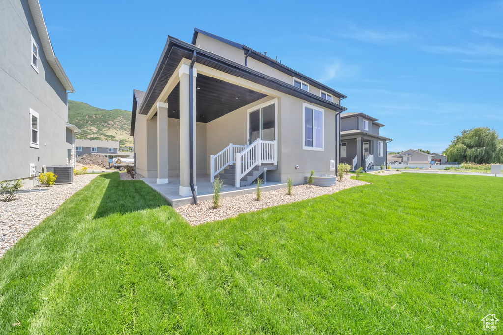 Back of house featuring cooling unit, stucco siding, a yard, a mountain view, and a patio area