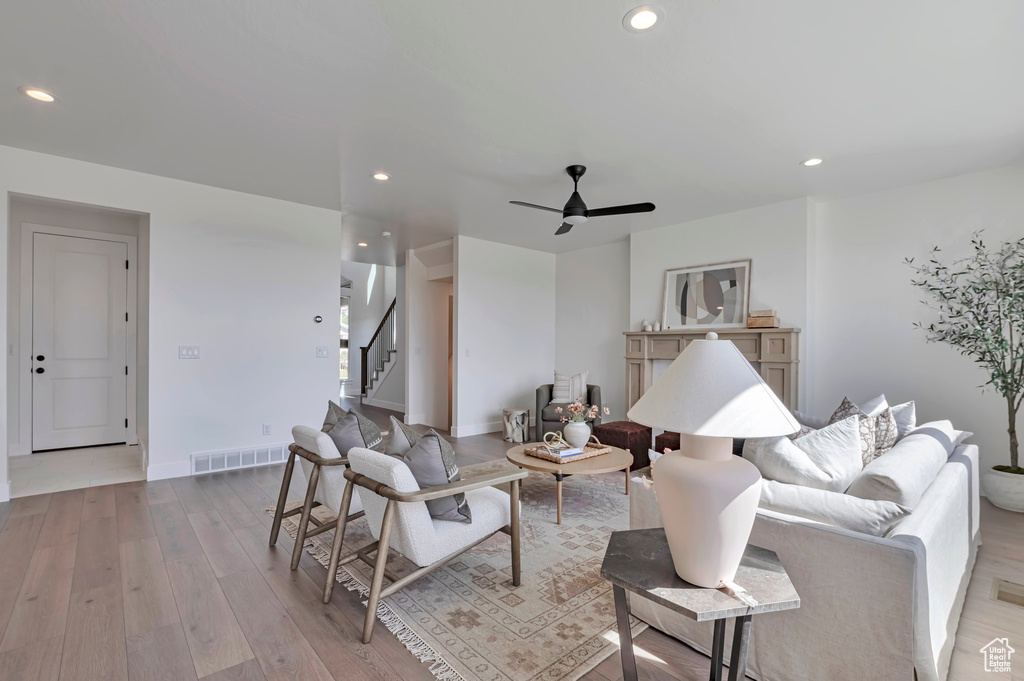 Living room with stairway, light wood-style flooring, a ceiling fan, and recessed lighting