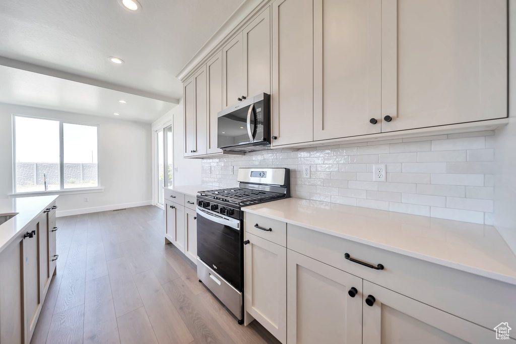 Kitchen featuring stainless steel appliances, baseboards, light wood-style floors, recessed lighting, and decorative backsplash