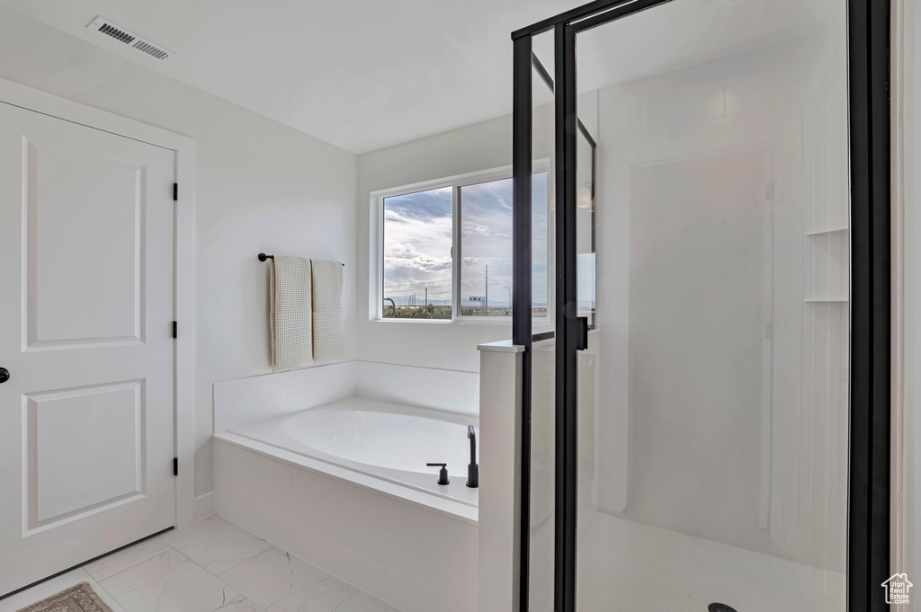 Bathroom with a stall shower, a bath, and marble look tiles