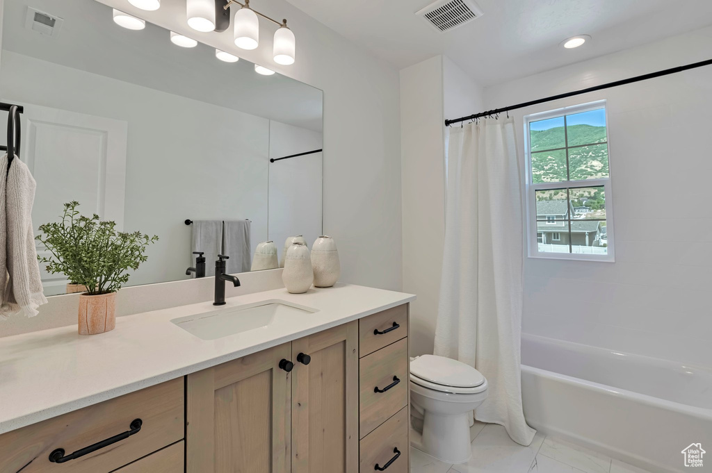 Bathroom featuring vanity, shower / bath combo with shower curtain, and recessed lighting