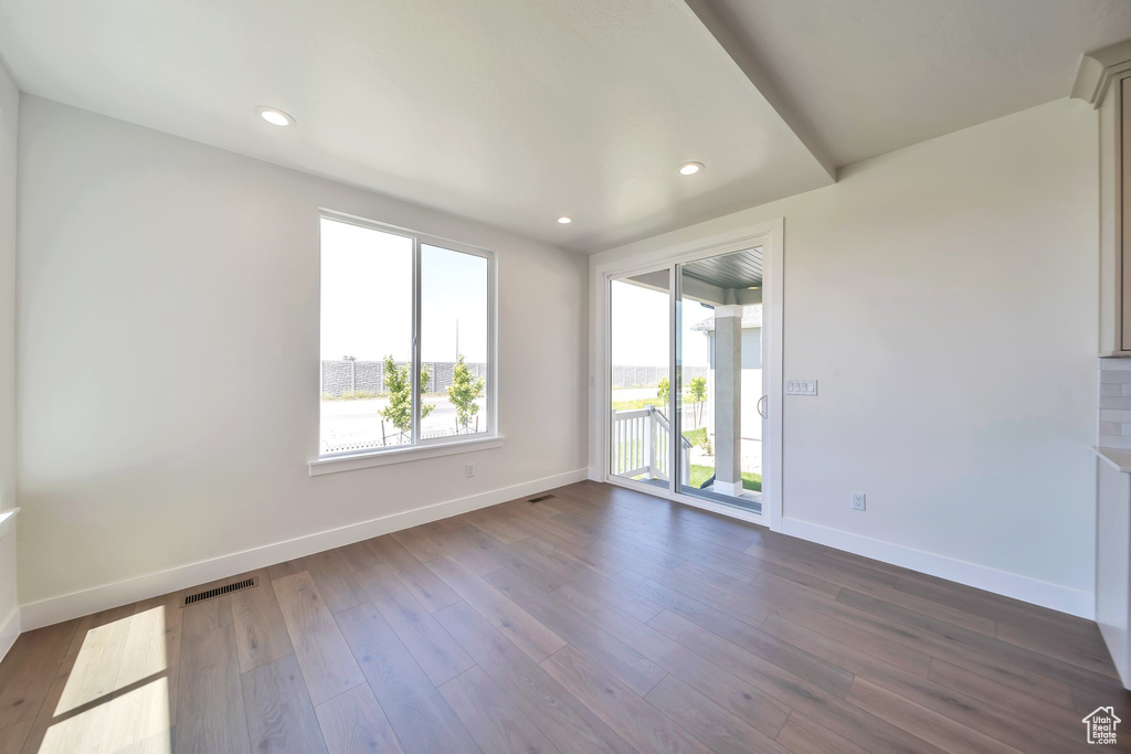 Spare room featuring baseboards, dark wood-type flooring, and recessed lighting