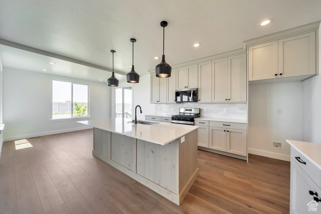 Kitchen featuring a sink, stainless steel appliances, baseboards, backsplash, and light countertops