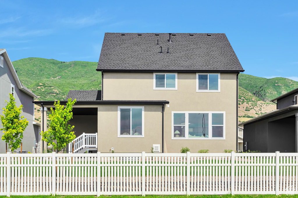Rear view of house with a mountain view, stucco siding, and a fenced backyard