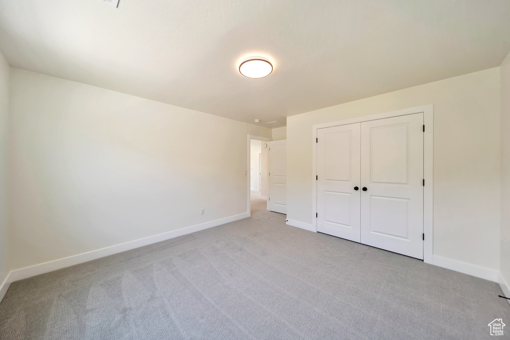 Unfurnished bedroom with light carpet and baseboards