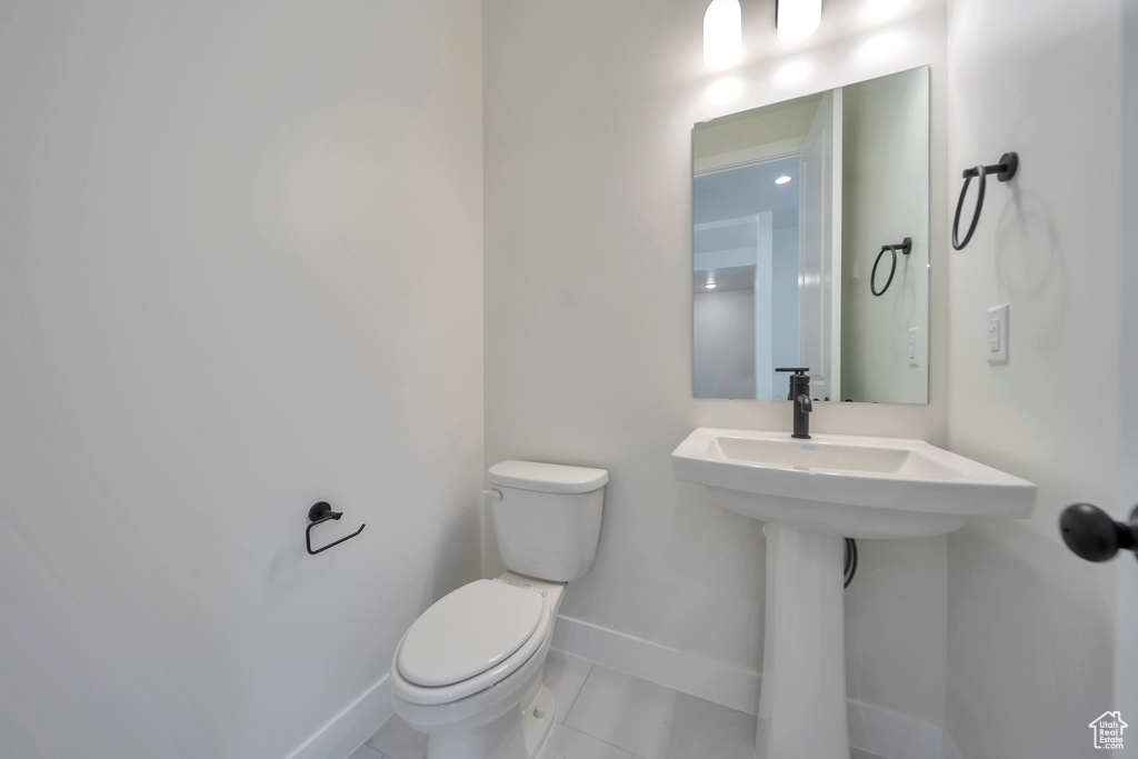 Bathroom featuring toilet, baseboards, and tile patterned floors