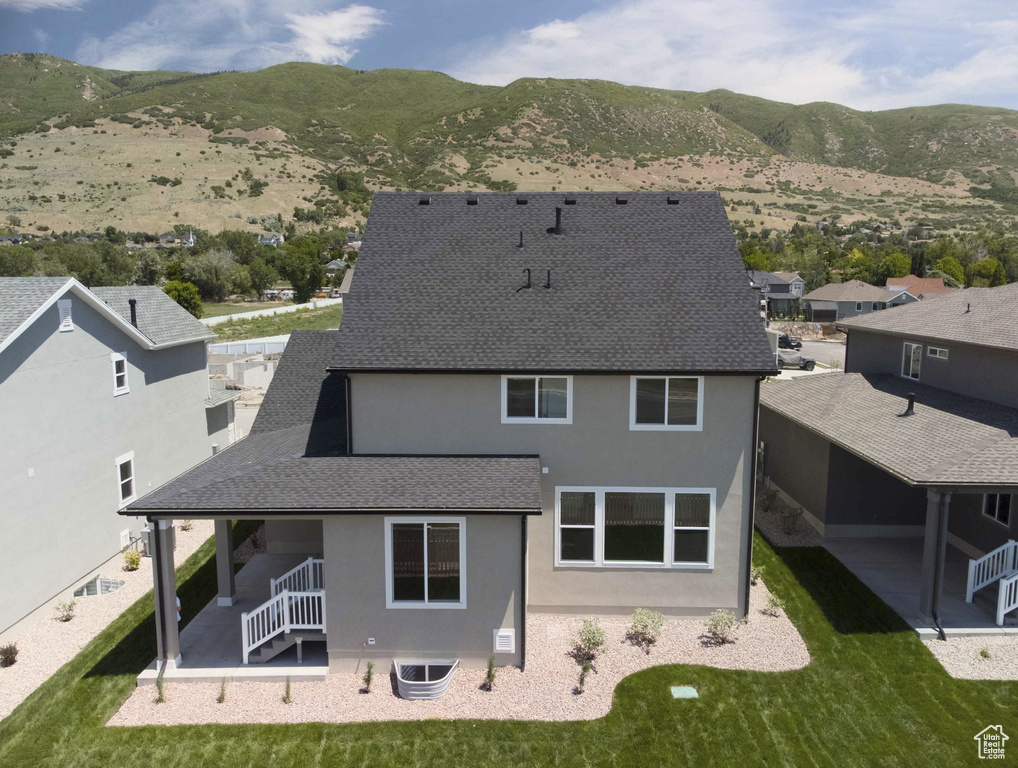 Rear view of house with stucco siding, roof with shingles, and a mountain view