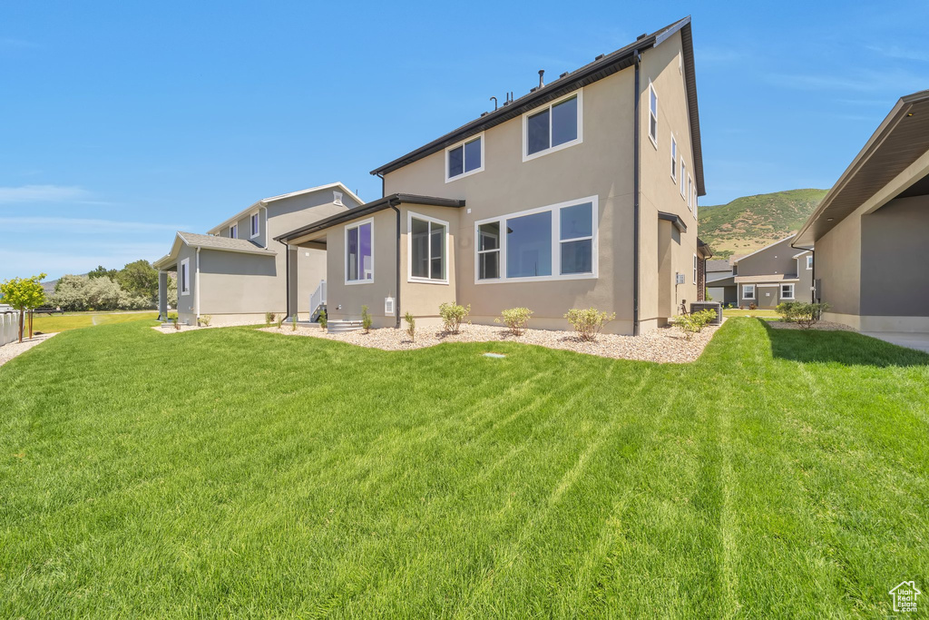 Rear view of house with stucco siding and a lawn