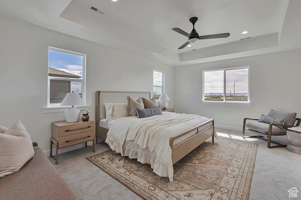 Bedroom with a tray ceiling, light carpet, recessed lighting, and a ceiling fan