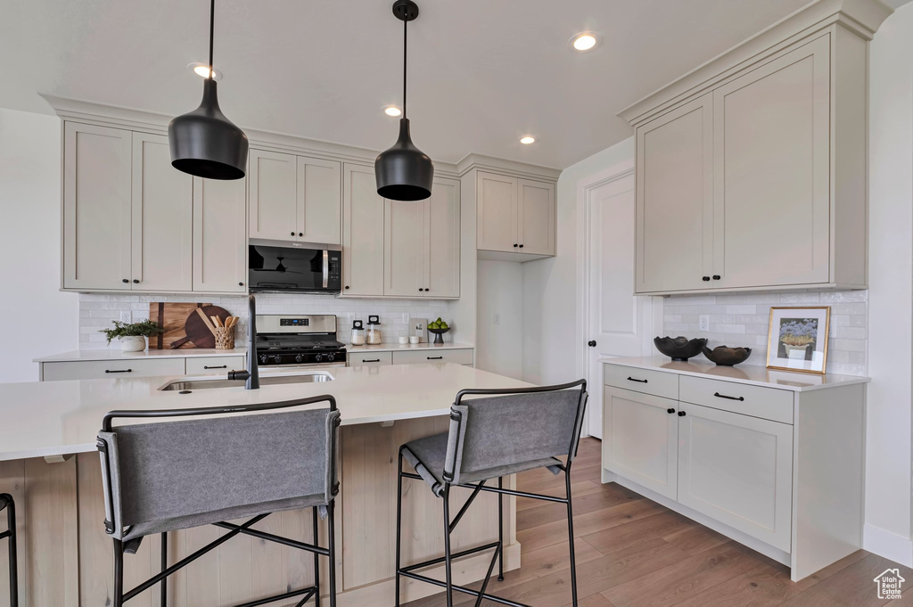 Kitchen with appliances with stainless steel finishes, decorative backsplash, light countertops, a breakfast bar area, and recessed lighting