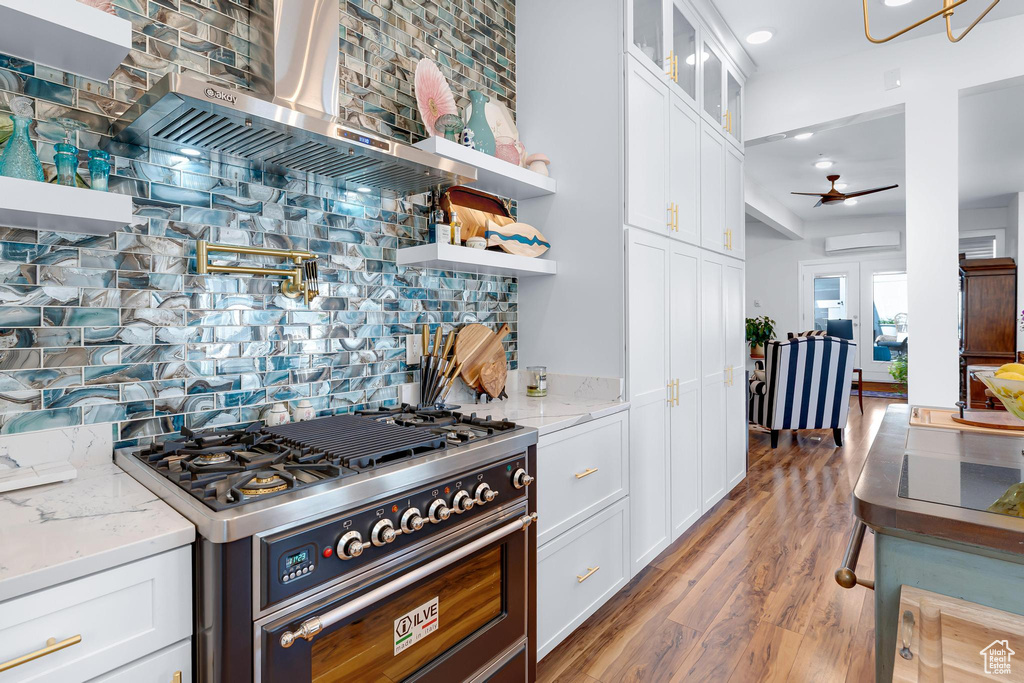 Kitchen featuring high end stainless steel range, open shelves, backsplash, a ceiling fan, and white cabinetry