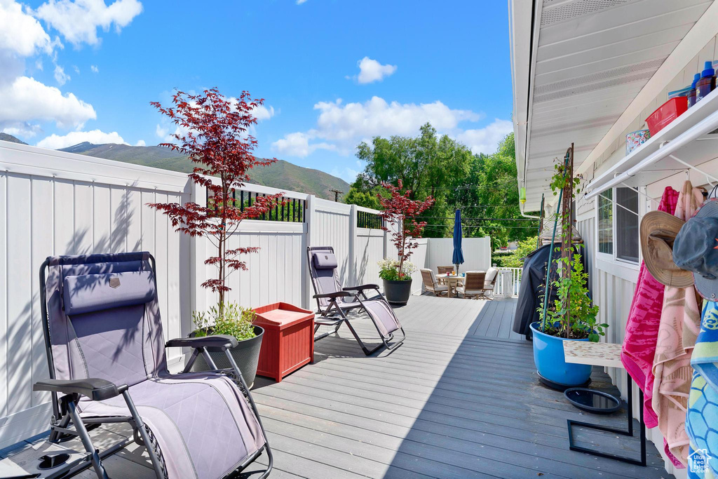 Wooden deck featuring a mountain view, outdoor dining area, and a fenced backyard