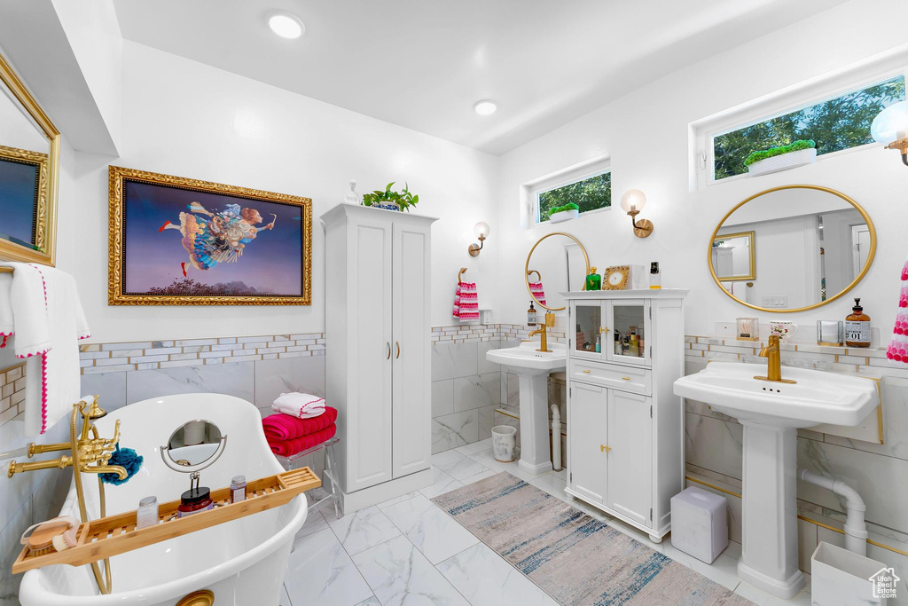 Bathroom featuring tile walls, a freestanding tub, marble finish floors, a wainscoted wall, and recessed lighting