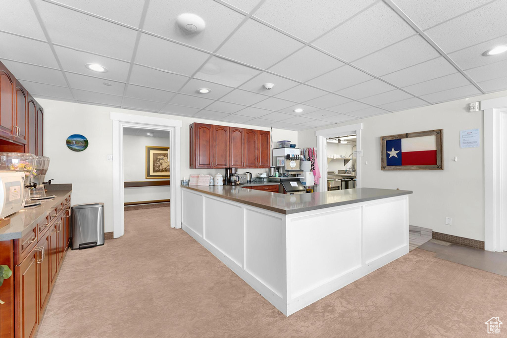 Kitchen with baseboards, light carpet, recessed lighting, a peninsula, and brown cabinetry