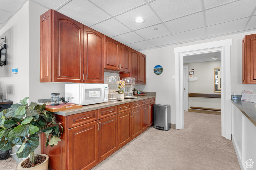Kitchen with white microwave, light carpet, a paneled ceiling, recessed lighting, and light countertops