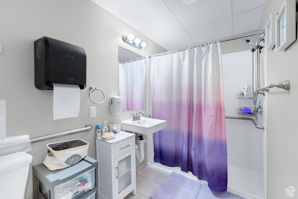 Bathroom featuring a shower with curtain, toilet, and a drop ceiling