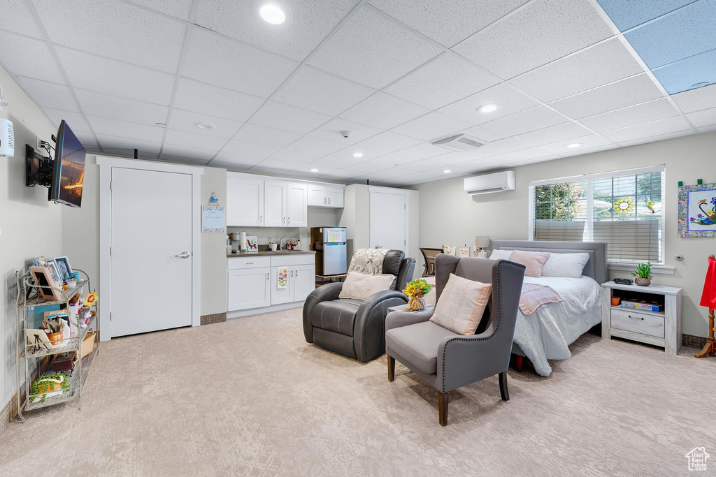 Bedroom with light carpet, a drop ceiling, an AC wall unit, and recessed lighting
