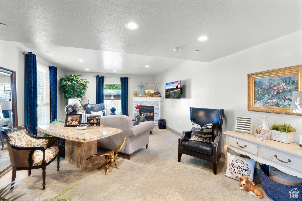 Living area with a glass covered fireplace, a textured ceiling, recessed lighting, light carpet, and baseboards