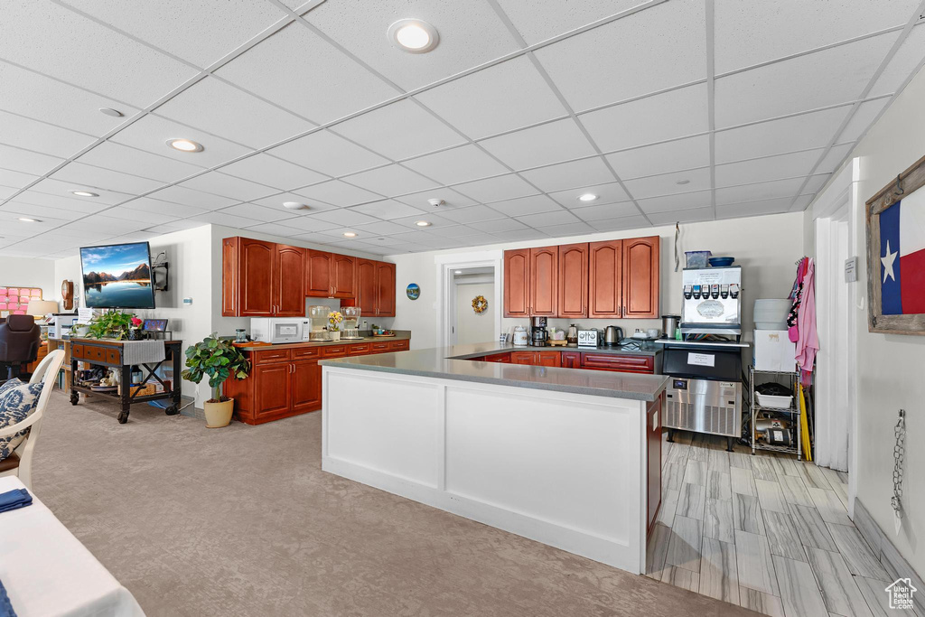 Kitchen with white microwave, a kitchen island, recessed lighting, a drop ceiling, and dark countertops