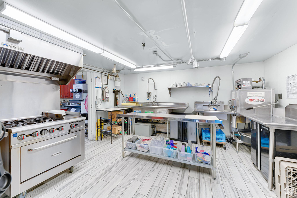 Kitchen featuring stainless steel countertops, premium stove, exhaust hood, and wood tiled floors