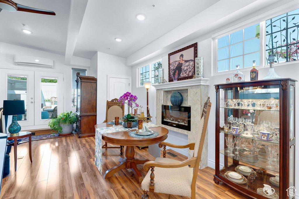 Living area featuring a wall unit AC, a premium fireplace, wood finished floors, french doors, and recessed lighting