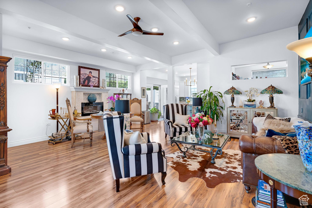 Living room featuring wood finished floors, a glass covered fireplace, a ceiling fan, recessed lighting, and beam ceiling