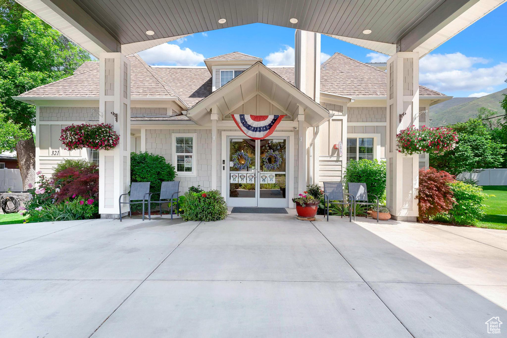 View of exterior entry featuring a shingled roof and french doors