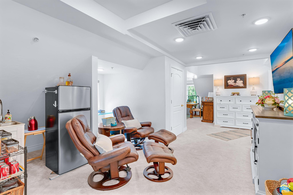 Living area with light carpet, recessed lighting, and baseboards