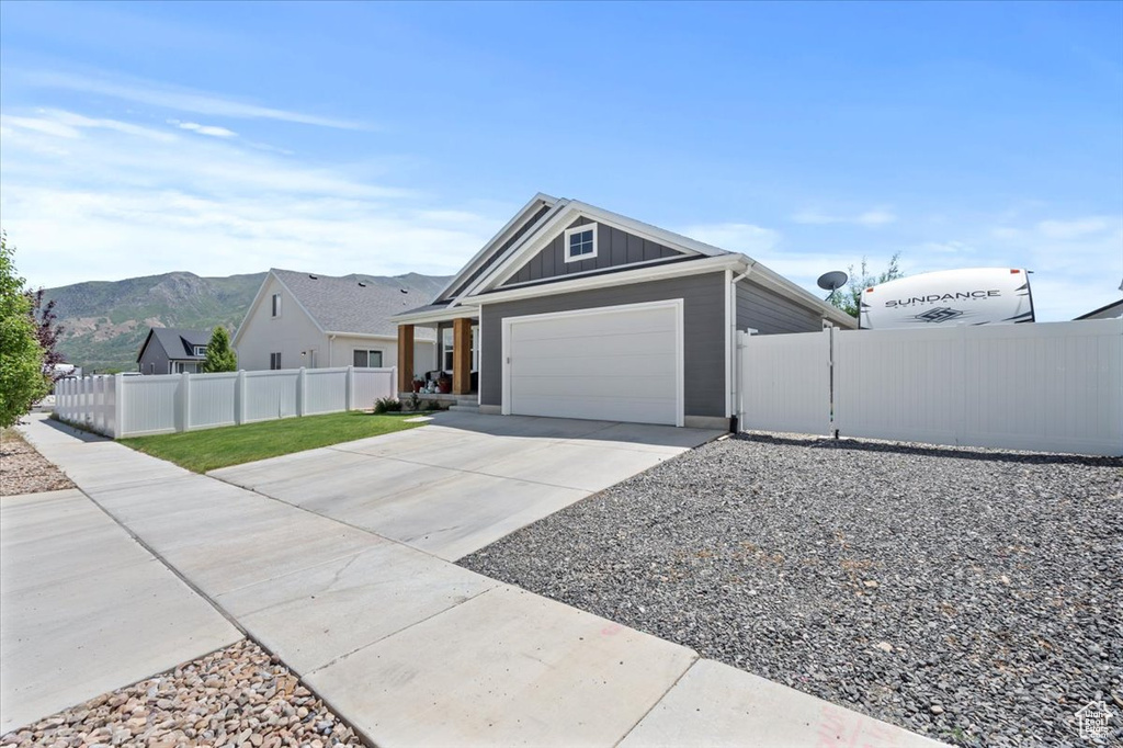 Ranch-style home featuring concrete driveway, board and batten siding, an attached garage, and a mountain view