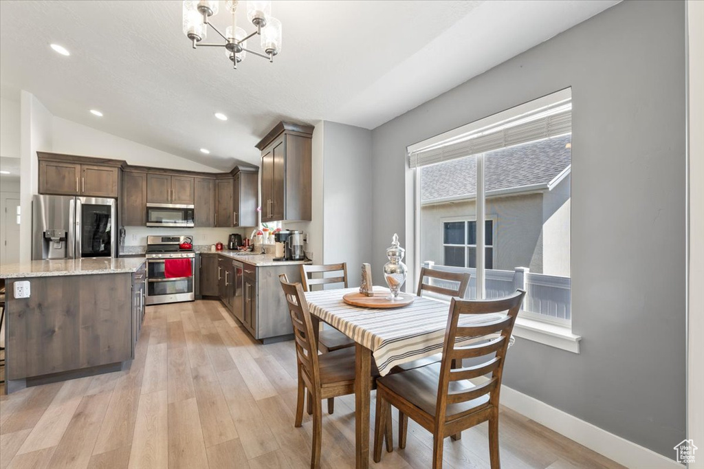 Dining space featuring light wood-style floors, vaulted ceiling, a chandelier, recessed lighting, and baseboards